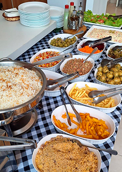 Mesa de buffet completa com arroz, farofa e acompanhamentos variados