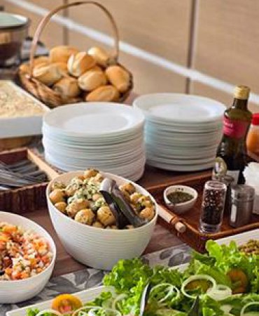 Mesa de buffet com louças e saladas servida em domicílio